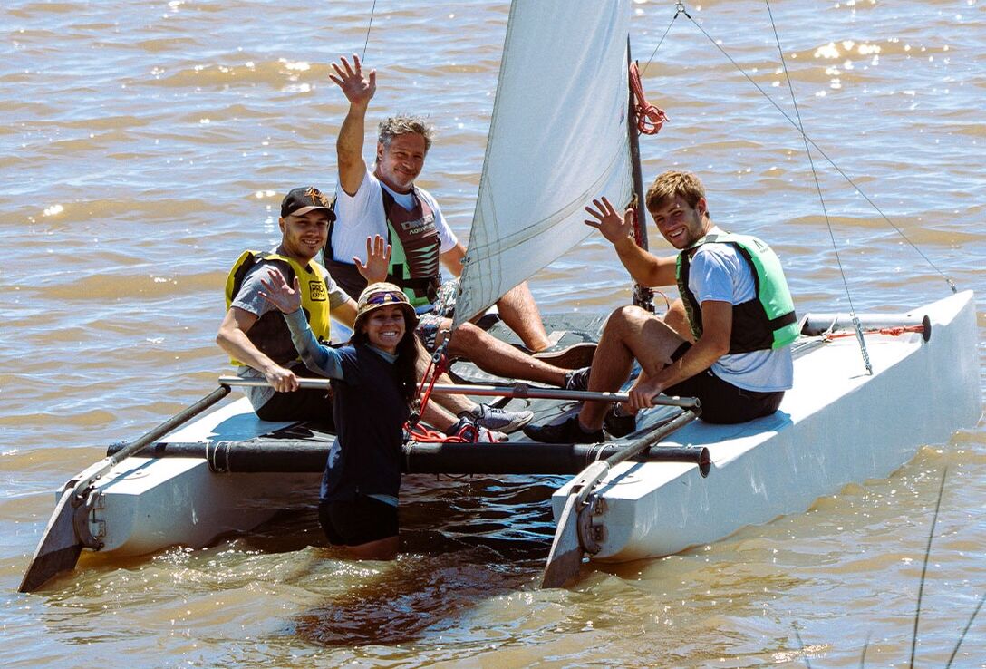 Un grupo navegando en catamarán en el río, saludando a cámara
